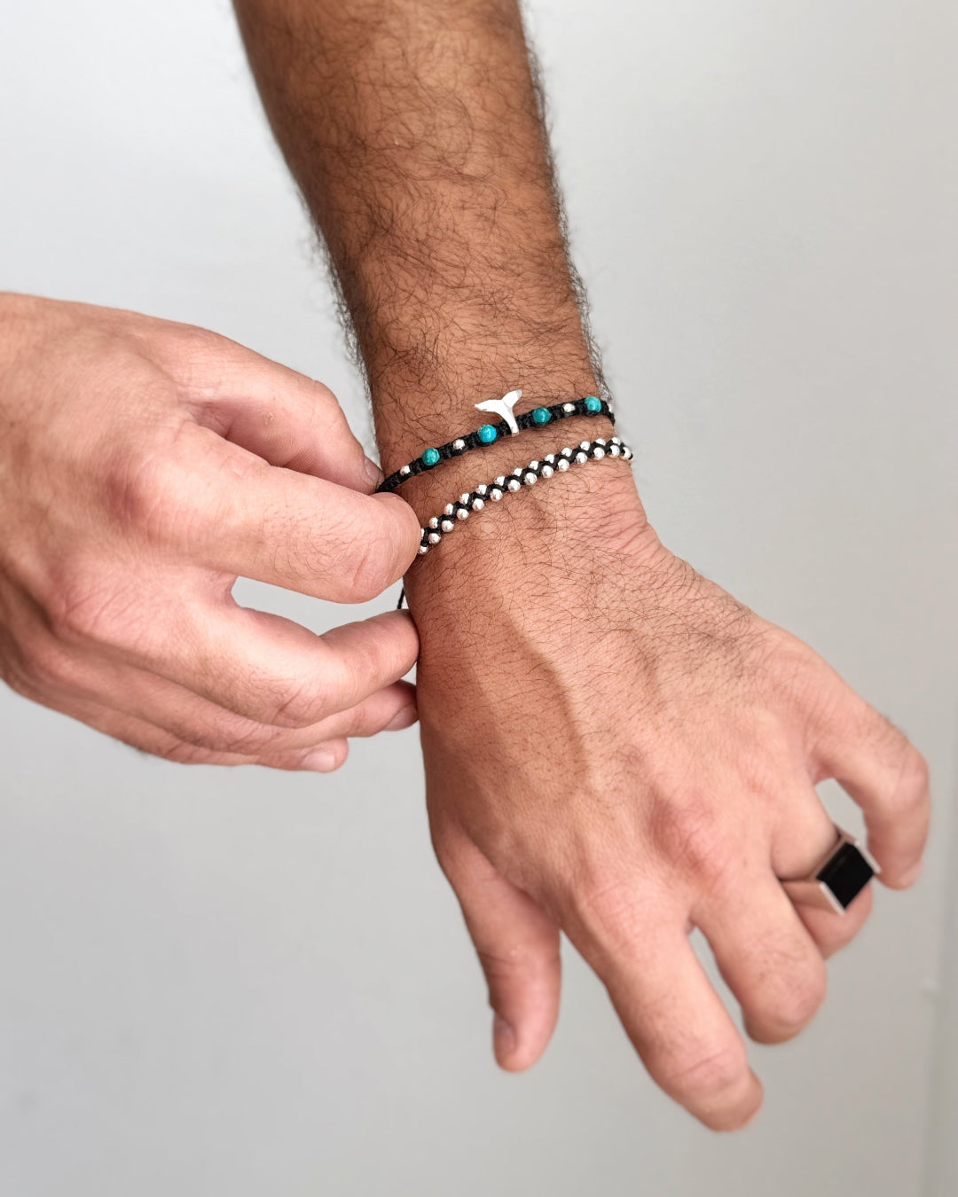 צמיד Triton בעבודת יד, מקרמה שחור, עם חרוזי טורקיז טבעית ותליון סנפיר כסף במרכז.