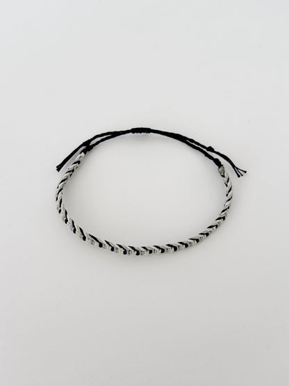 צמיד Tide מקרמה לגבר בעבודת יד על רקע בהיר, בגווני שחור ותכלת-אפרפר.