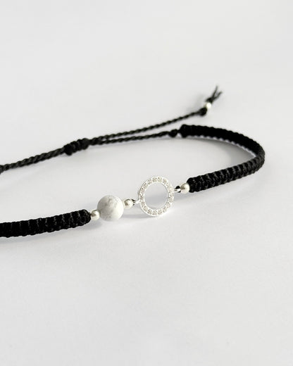 צמיד מקרמה עדין מדגם Halo, עם אלמנט עגול מצופה זרקונים ואבן Howlite לבנה, מצולם על רקע נקי