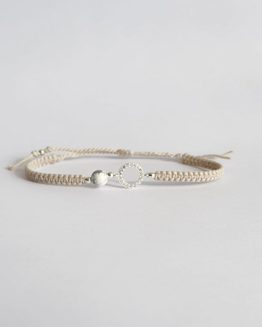 צמיד מקרמה עדין מדגם Halo, עם אלמנט עגול מצופה זרקונים ואבן Howlite לבנה, מצולם על רקע נקי