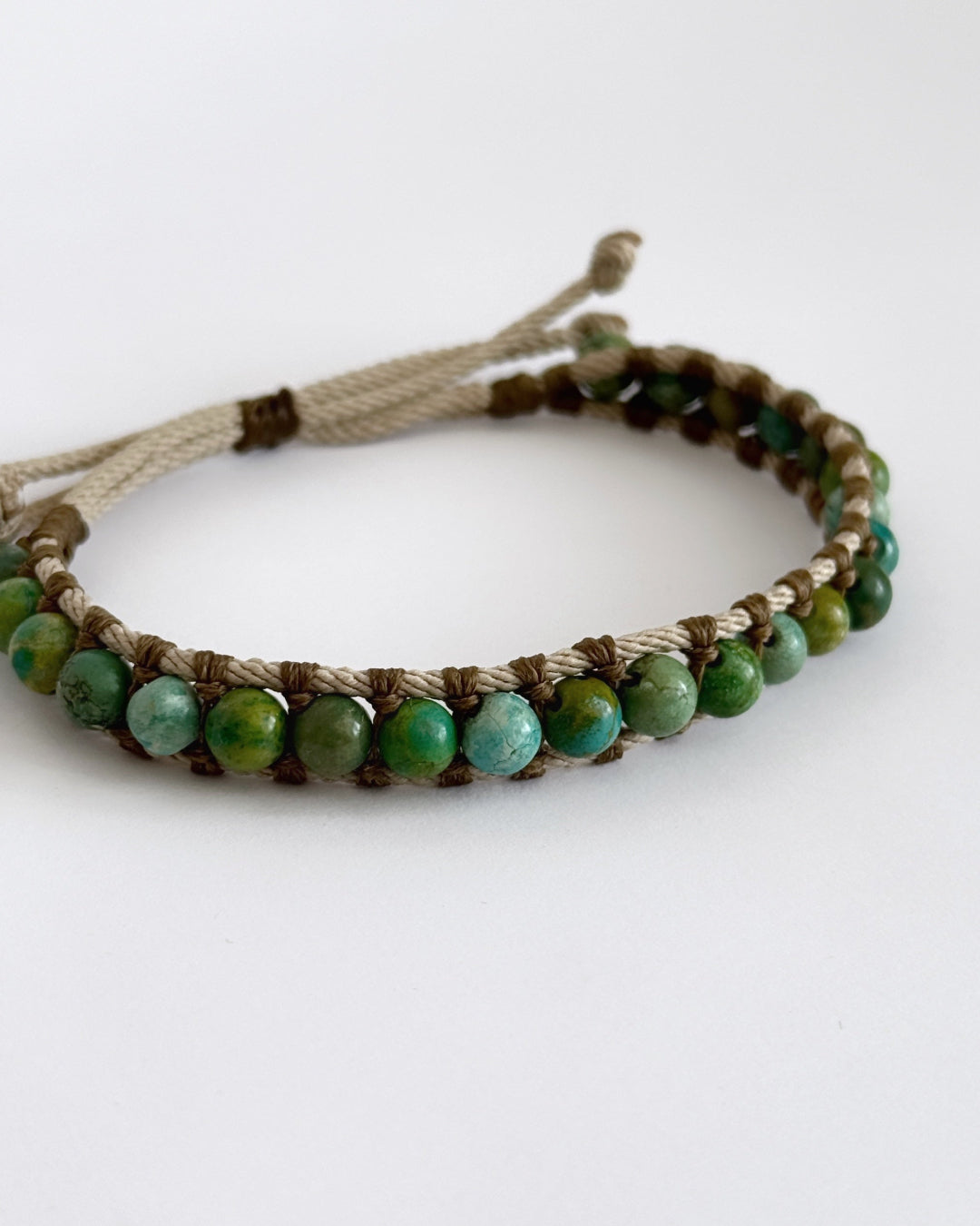 צמיד Creek בעבודת יד עם חרוזי טורקיז אפריקאי וחוטים טבעיים בגווני ירוק ומים על רקע בהיר