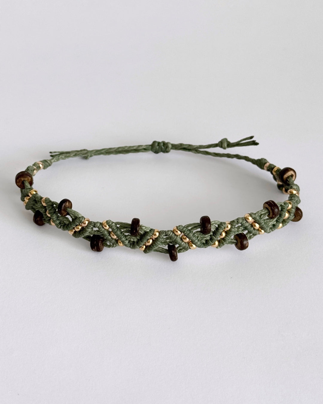 צמיד מקרמה Grove בירוק זית עם חרוזי עץ כהים וחרוזים מוזהבים, מצולם על רקע נקי.