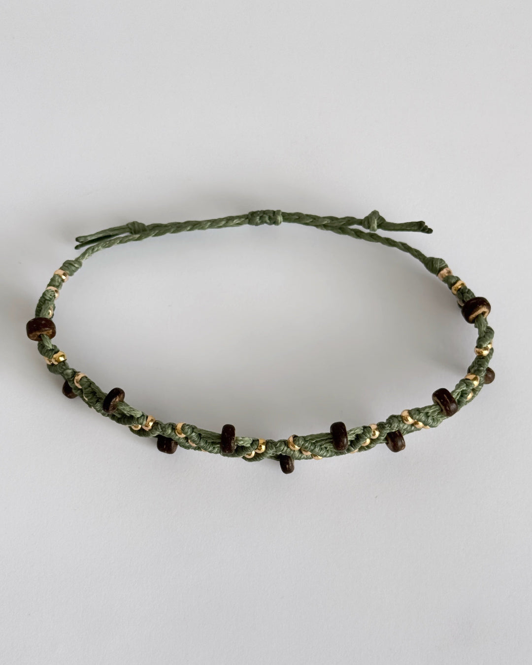 צמיד מקרמה Grove בירוק זית עם חרוזי עץ כהים וחרוזים מוזהבים, מצולם על רקע נקי.