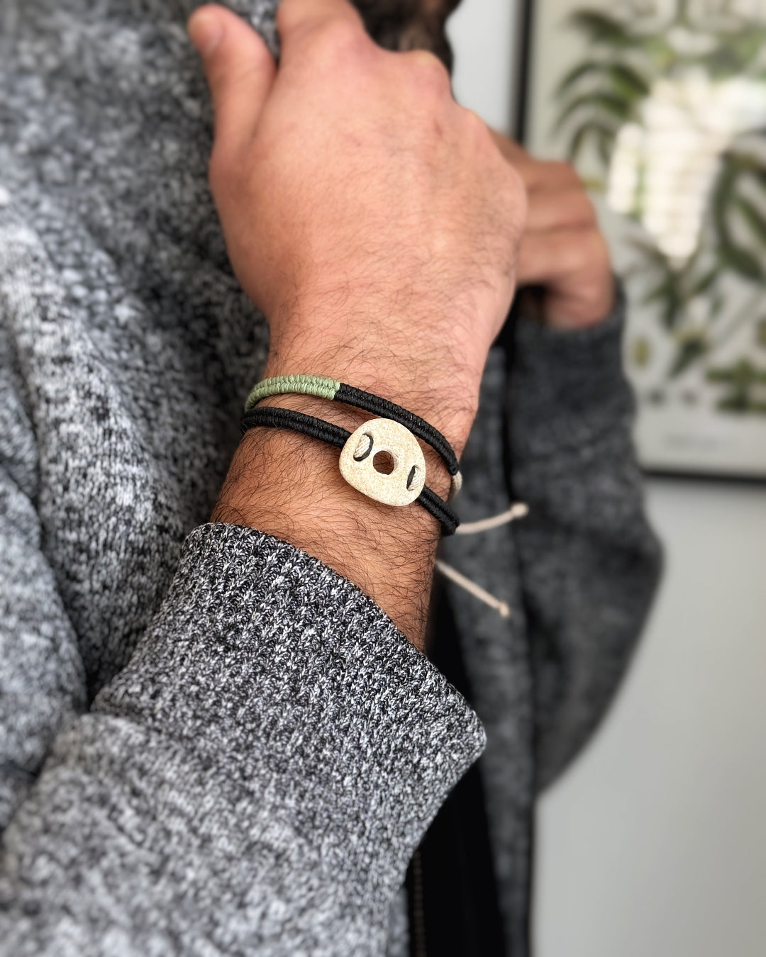 Minimalist handmade macramé bracelet with light pebble worn on wrist, unisex design