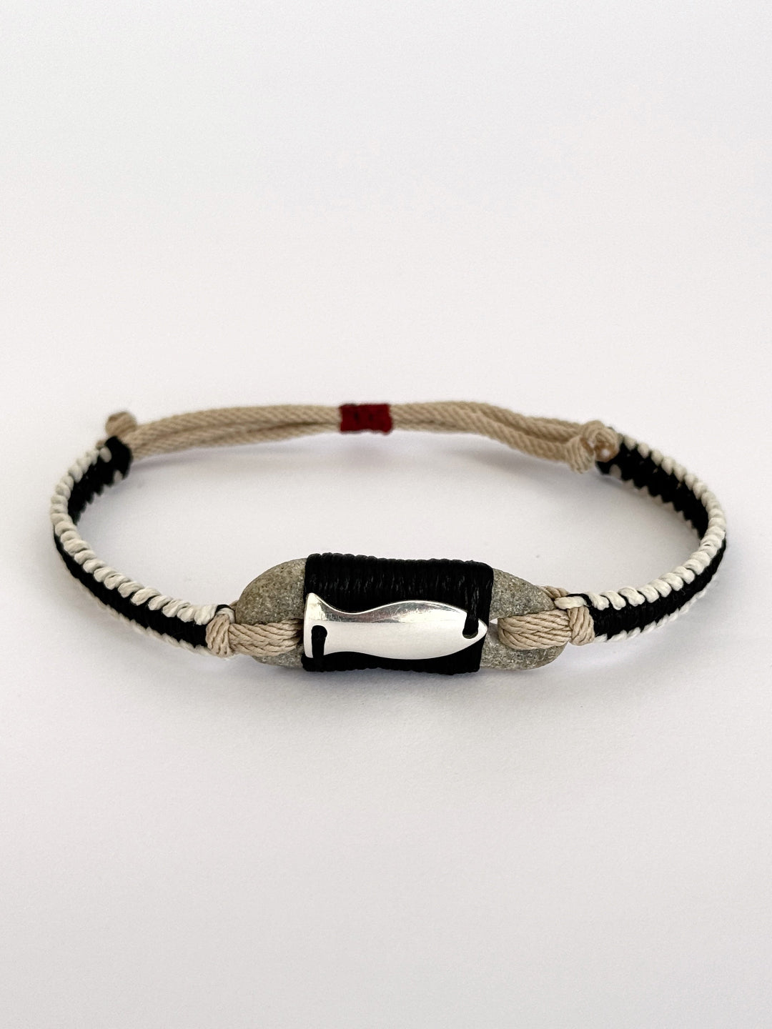 Macramé bracelet combining natural stone, black and beige cords, and silver fish charm