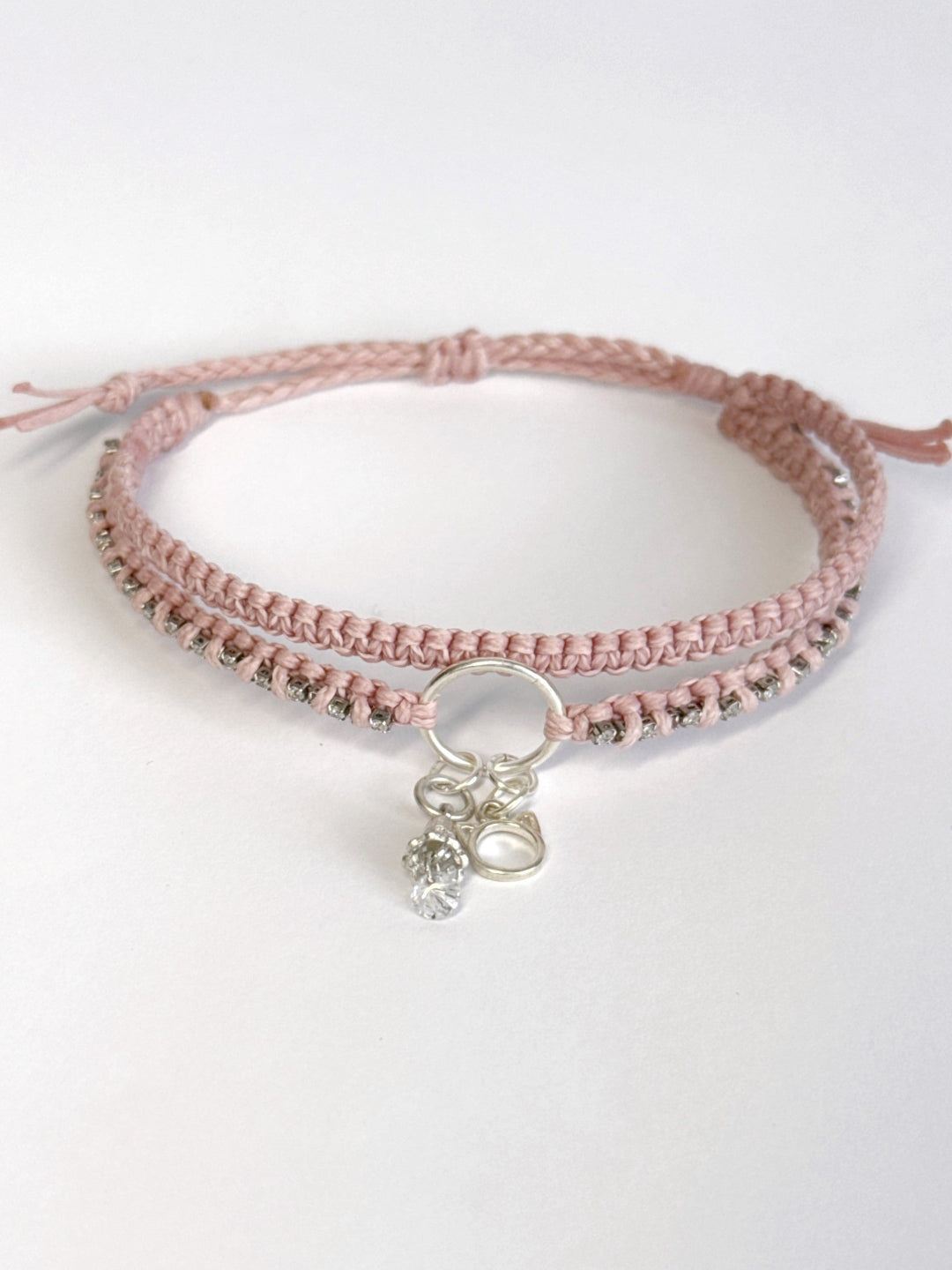 צמיד מקרמה כפול בגוון ורוד בייבי עם שרשרת זירקונים שזורה ותליוני כסף של חתול ופעמון - צמיד Stardust של Lala Fshasha.