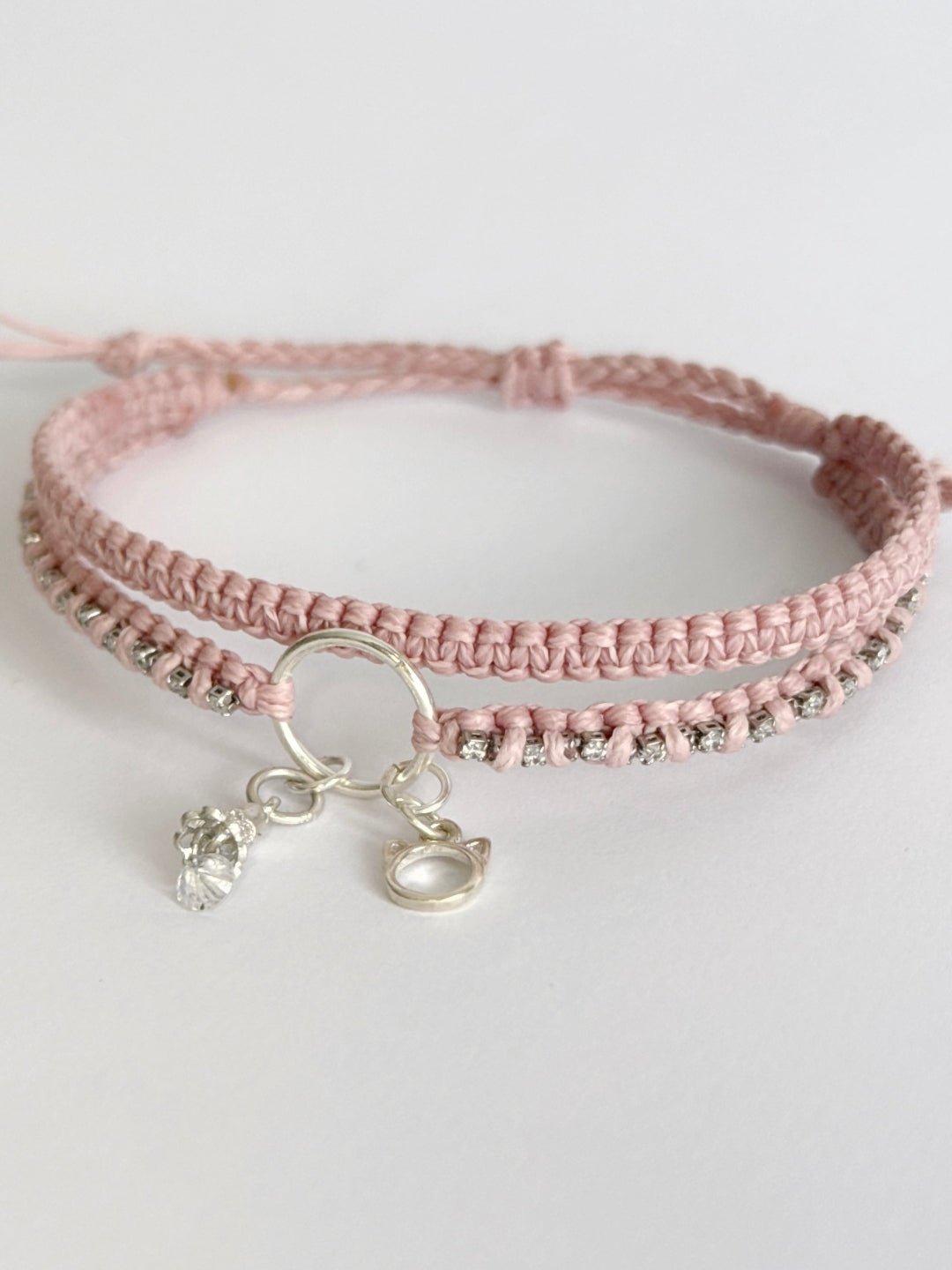 צמיד מקרמה כפול בגוון ורוד בייבי עם שרשרת זירקונים שזורה ותליוני כסף של חתול ופעמון - צמיד Stardust של Lala Fshasha.