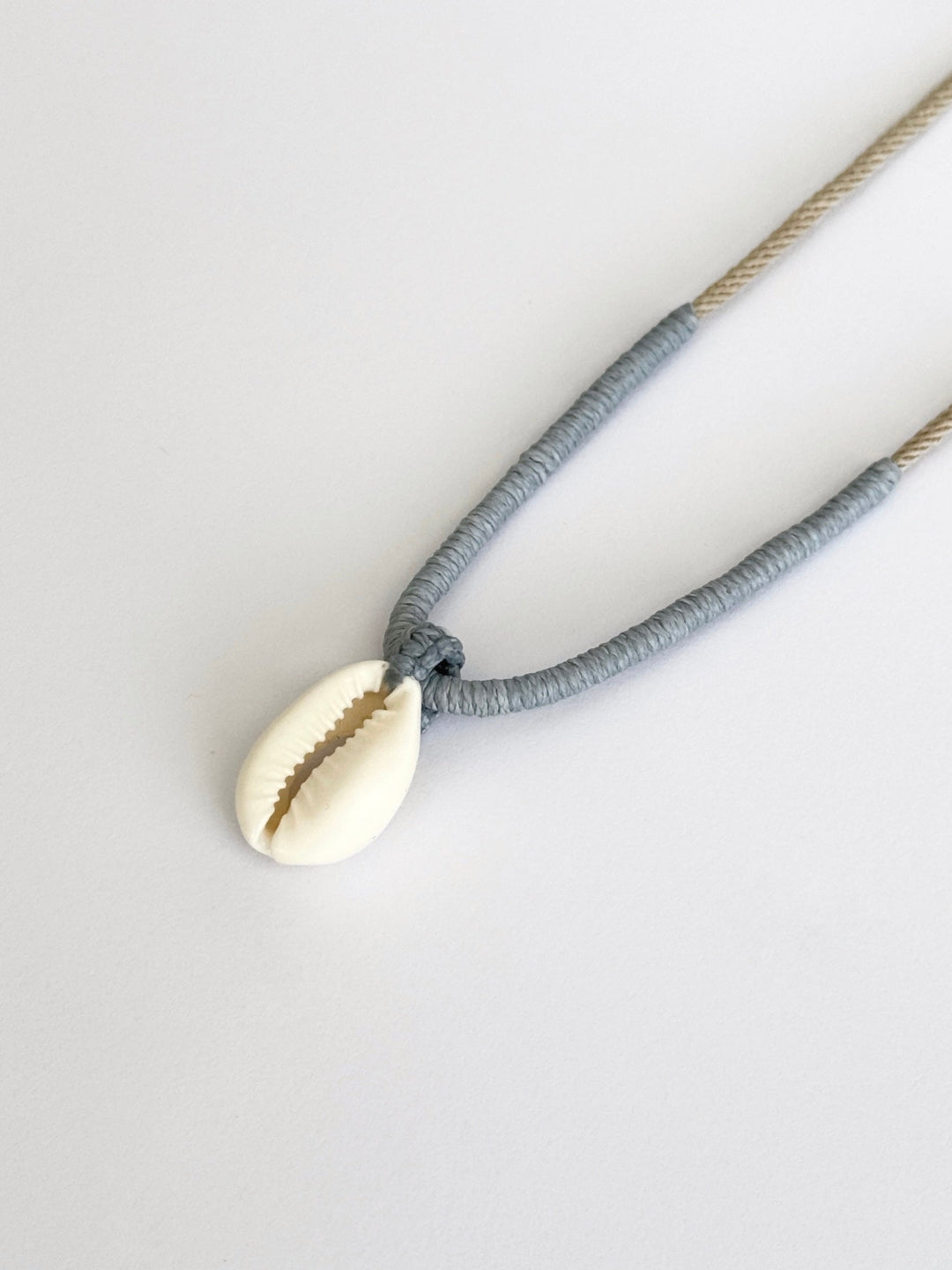 Cove Necklace: Natural Cowrie shell pendant with handcrafted macrame wrapping in smoky pastel tones by Lala Fshasha.